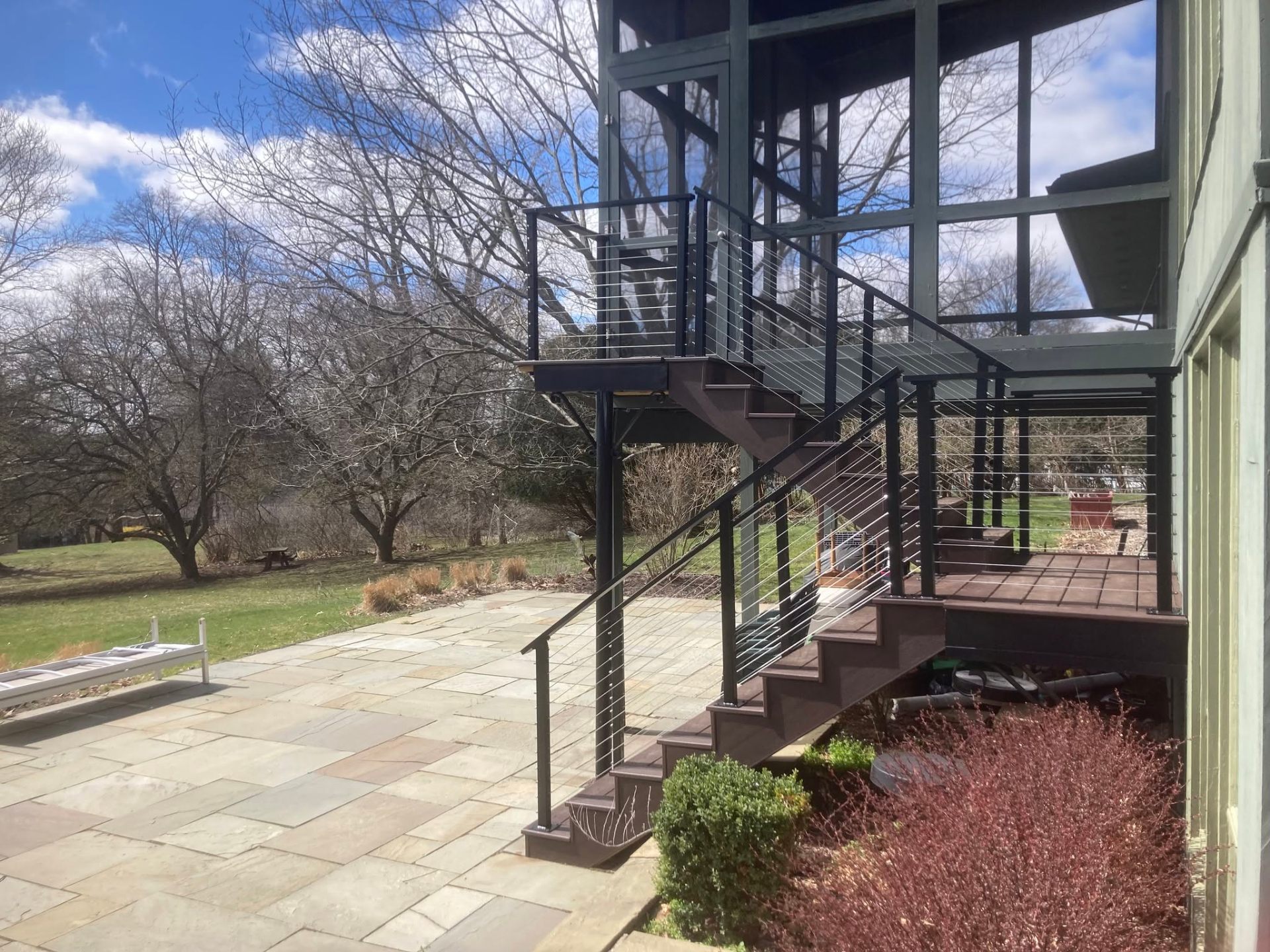 Dark stained wood staircase with stainless cable railing leading to an elevated deck