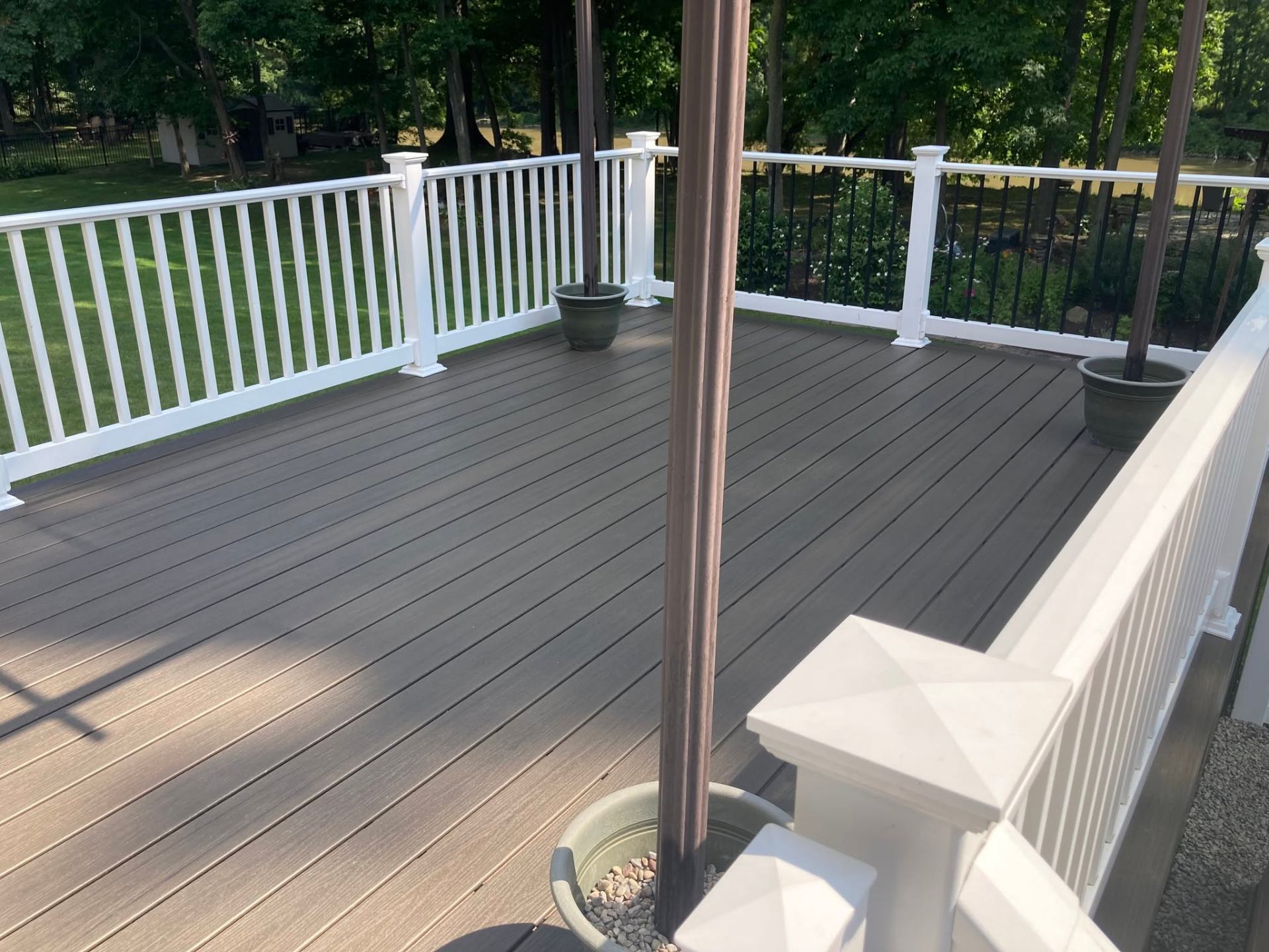 Trex Coastal Bluff composite deck with white vinyl railing and black balusters overlooking a wooded yard