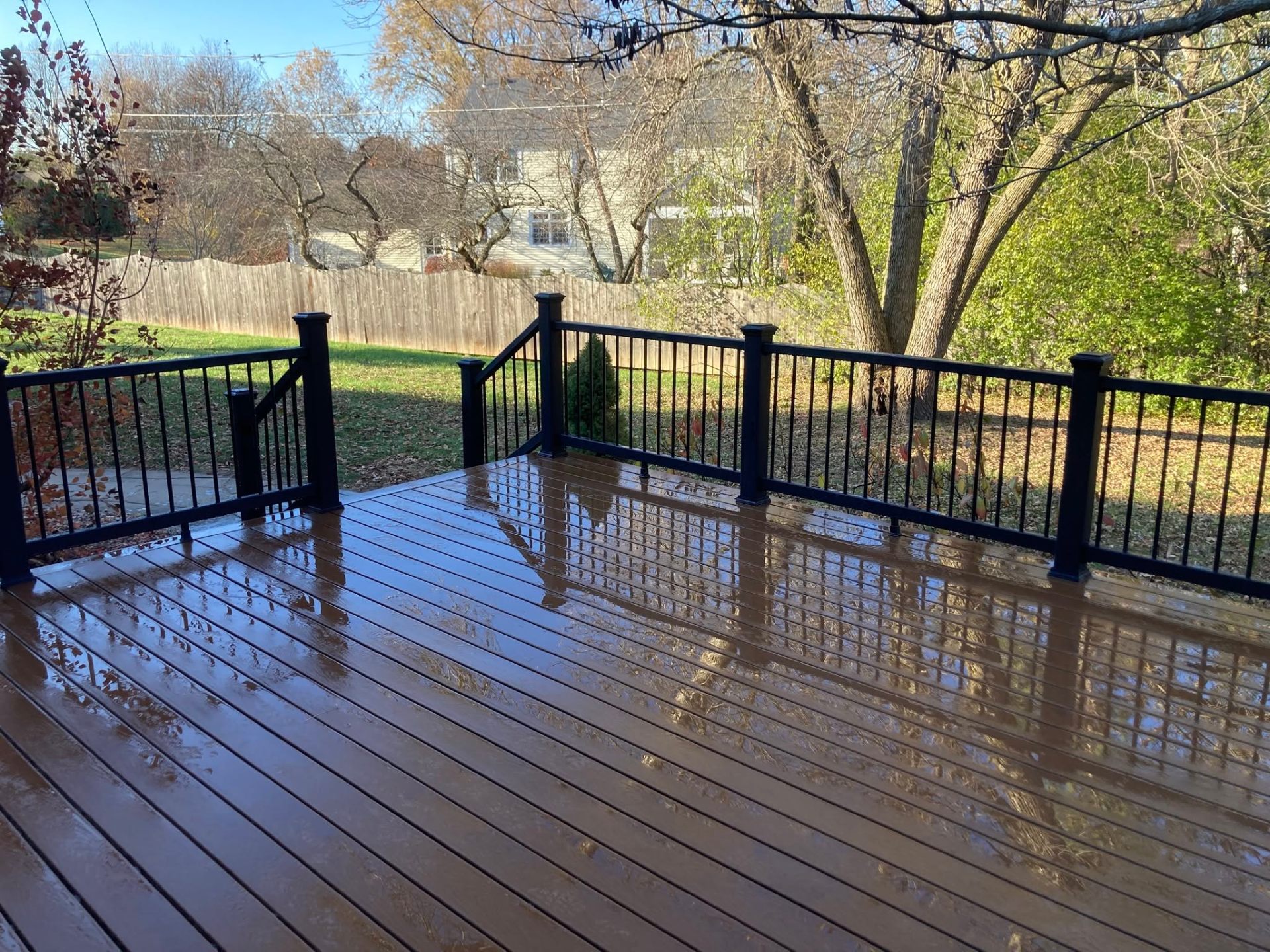 Brown composite deck with black aluminum railing photographed just after rain