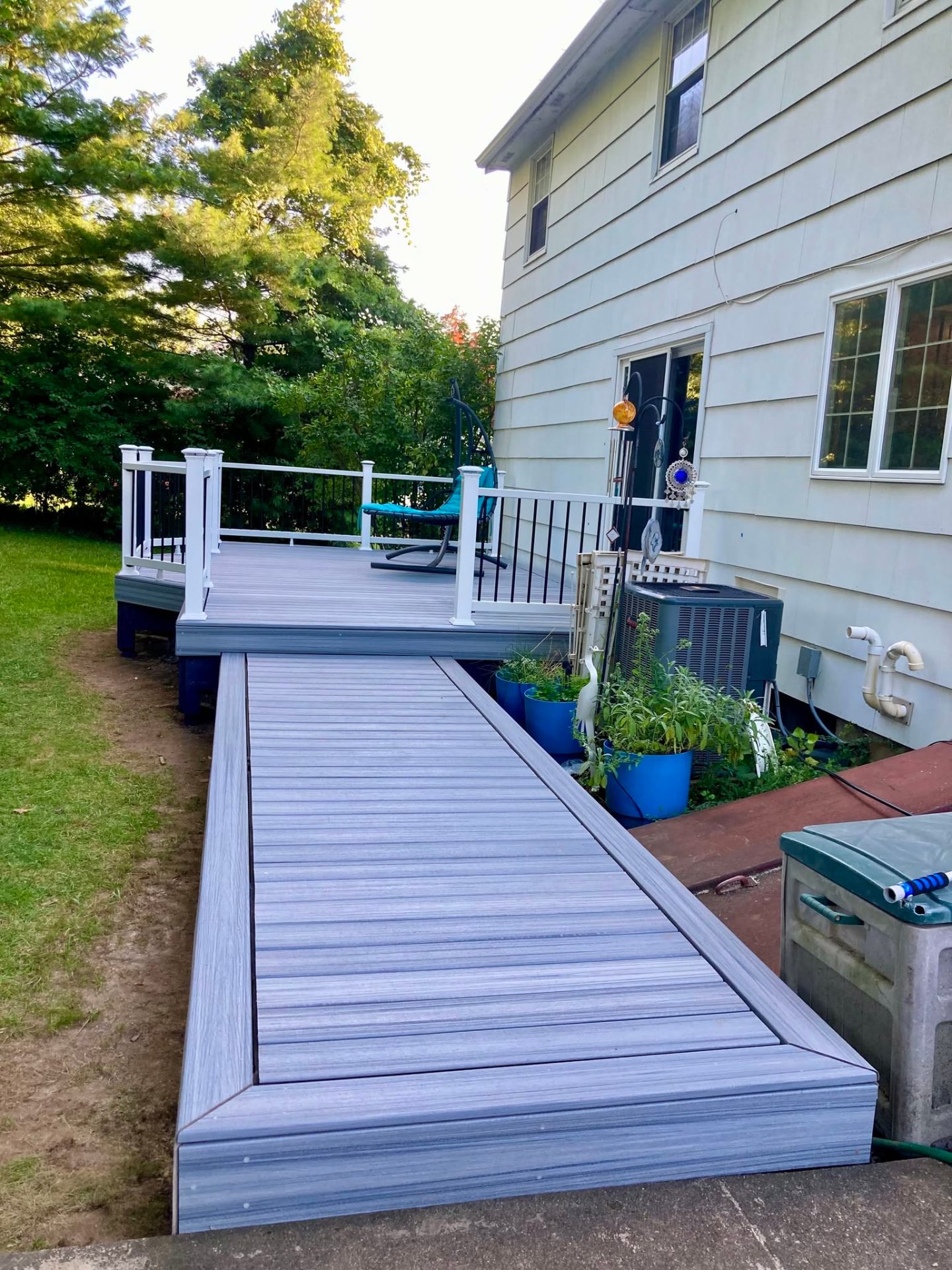 Gray composite deck with a long walkway extension running along the side of the house