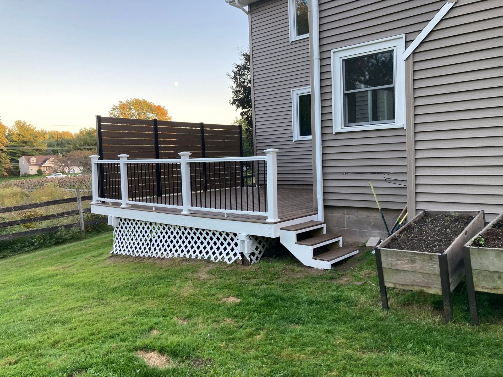 Side view of a brown composite deck with a short set of stairs to the yard